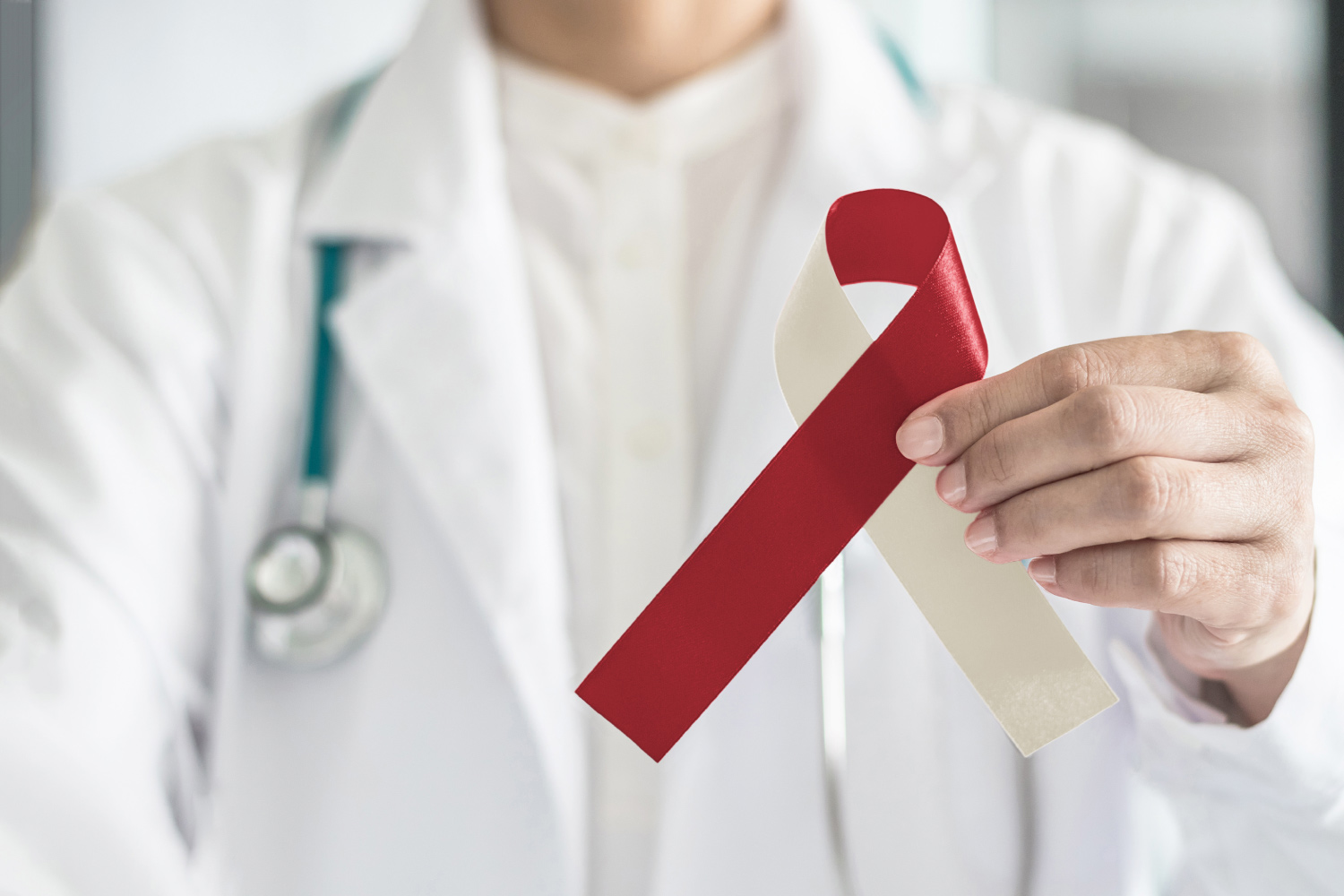 Dentist holds a red and beige cancer ribbon for oral cancer awareness