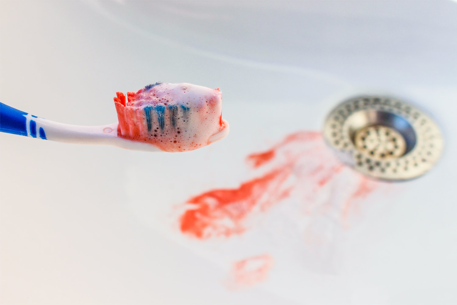 Blood on a toothbrush and blood in the sink from bleeding gums, one of the signs of gum disease