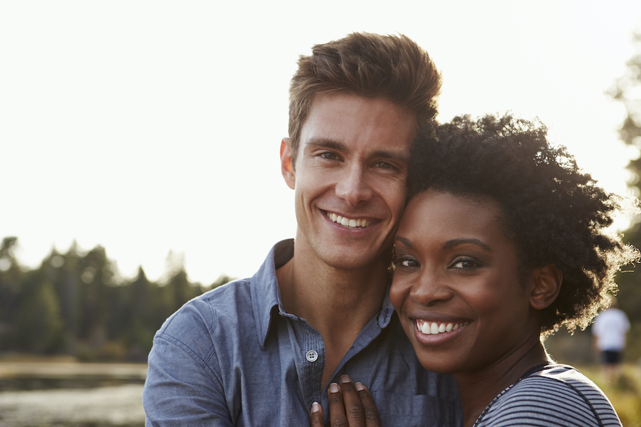 Black and white couple smile as they embrace outside, dentist in bentonville