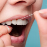 closeup of a woman flossing her teeth with string floss to keep her teeth and gums healthy