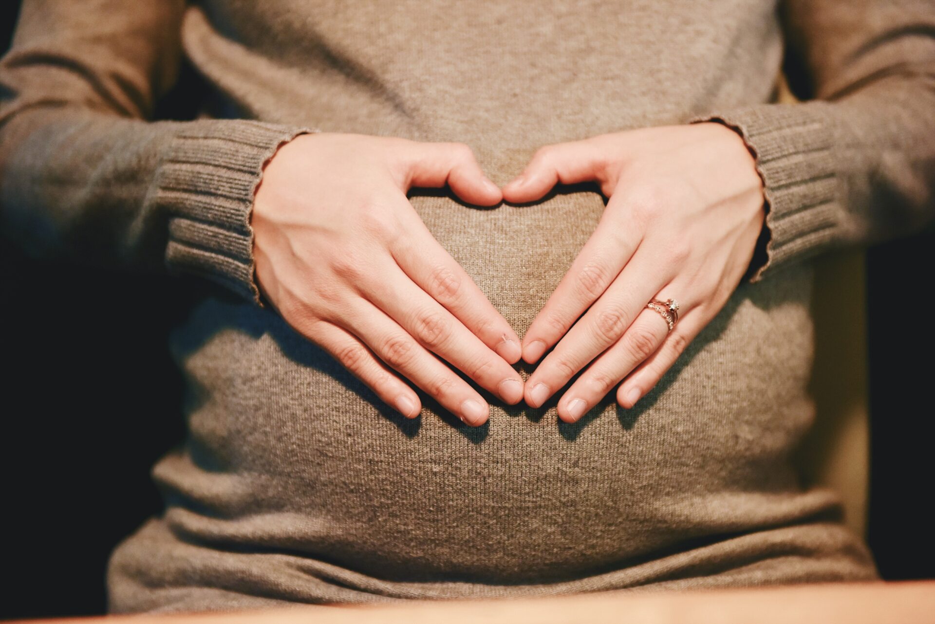 Closeup of a pregnant belly with the mom's hands in a heart shape