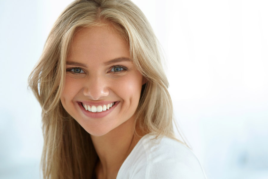 young woman smiles showing off her professional teeth whitening results, dentist in bentonville