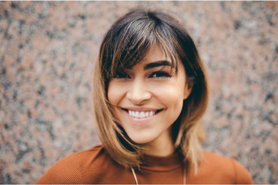 young woman smiles showing off her dental veneers