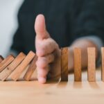 image of a hand stopping dominos tipping over, preventive dental care can prevent problems