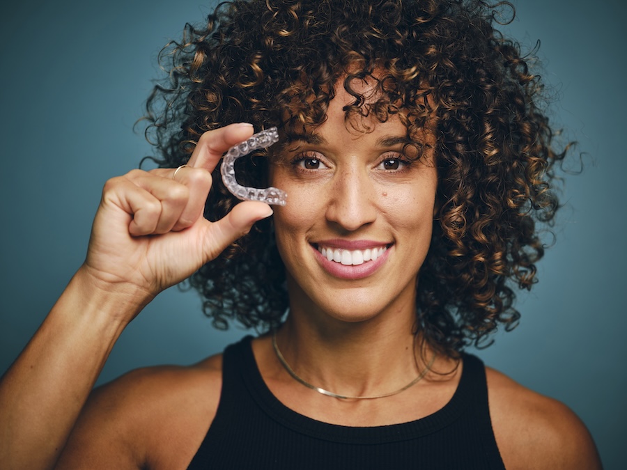 woman holding invisalign clear aligner tray needing some invisalign cleaning tips